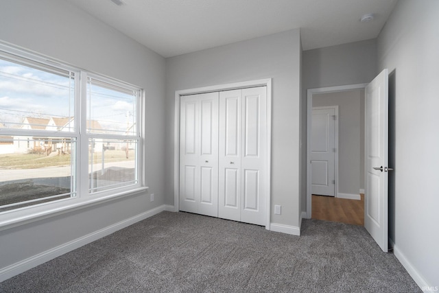 unfurnished bedroom with a closet and dark colored carpet