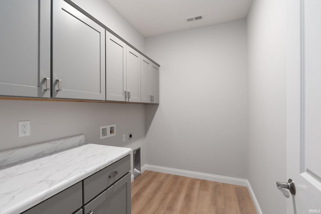 clothes washing area with hookup for a washing machine, light hardwood / wood-style flooring, cabinets, and hookup for an electric dryer