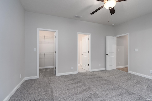 unfurnished bedroom with ceiling fan, a walk in closet, carpet floors, and a closet