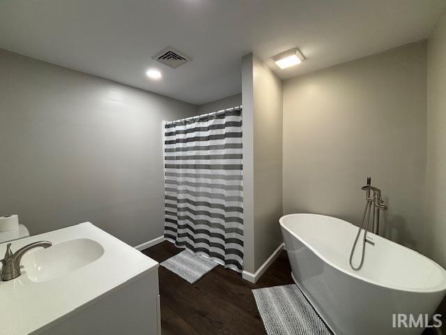 bathroom featuring a washtub, vanity, and wood-type flooring