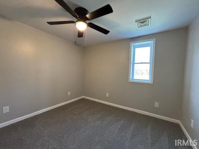 spare room with ceiling fan and dark carpet