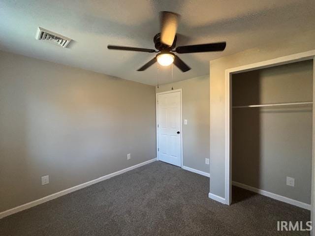 unfurnished bedroom with ceiling fan, a closet, and dark carpet