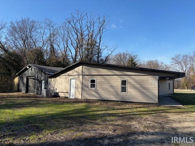 view of side of property with central air condition unit and a lawn