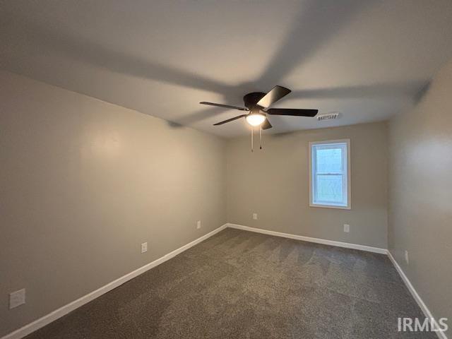 unfurnished room featuring ceiling fan and dark colored carpet