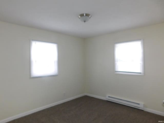 carpeted spare room featuring a baseboard heating unit