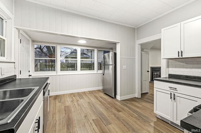 kitchen with sink, crown molding, light hardwood / wood-style flooring, white cabinetry, and stainless steel appliances