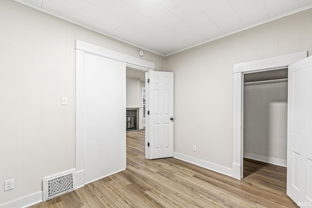 unfurnished bedroom with a closet, hardwood / wood-style floors, and ornamental molding