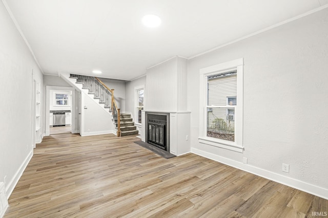 unfurnished living room featuring a wealth of natural light, crown molding, and light hardwood / wood-style floors