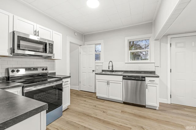 kitchen featuring sink, backsplash, appliances with stainless steel finishes, white cabinets, and light wood-type flooring