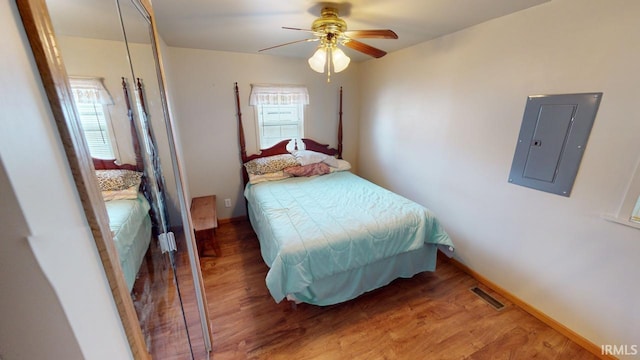 bedroom featuring hardwood / wood-style floors, electric panel, and ceiling fan