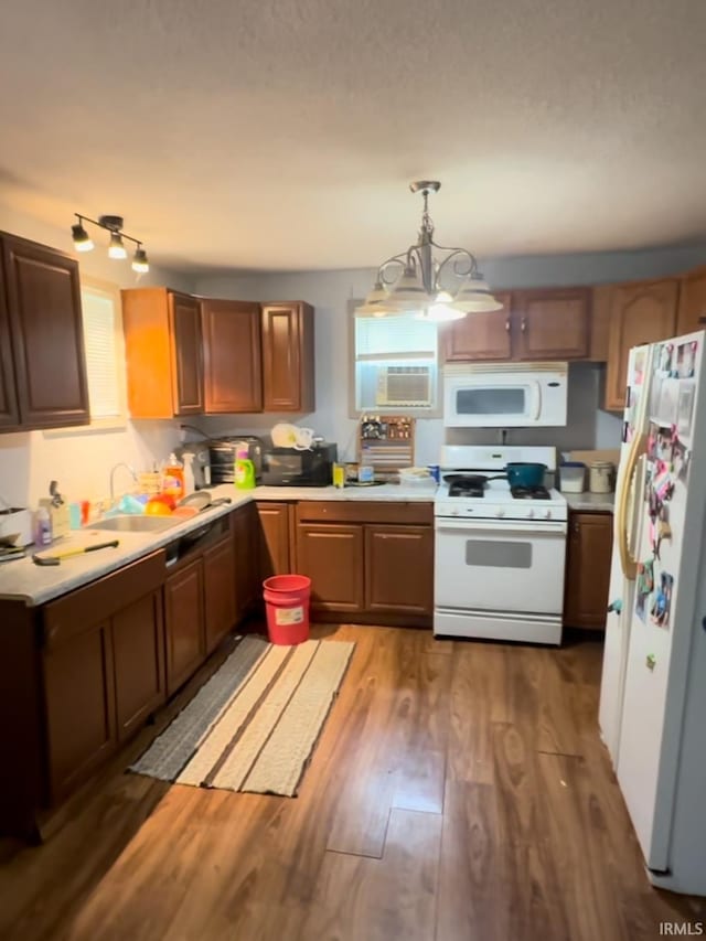 kitchen featuring white appliances, sink, a chandelier, dark hardwood / wood-style floors, and hanging light fixtures