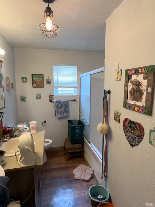 bathroom featuring vanity, wood-type flooring, a shower with shower door, and toilet