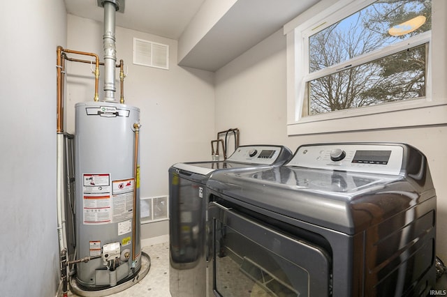 clothes washing area with washer and dryer and gas water heater