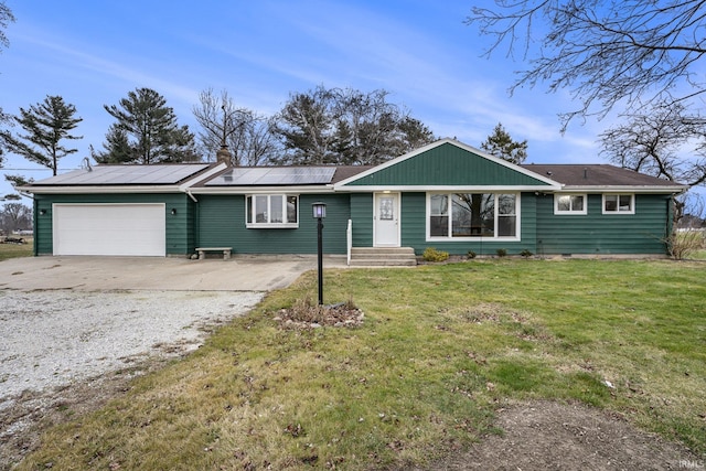 single story home featuring solar panels, a garage, and a front yard