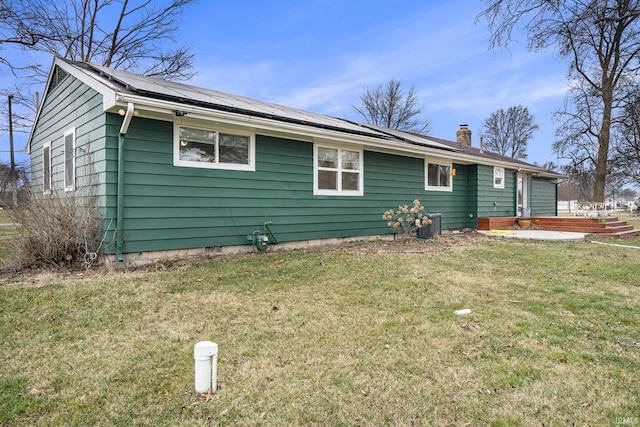 view of side of home with a wooden deck, a yard, and solar panels