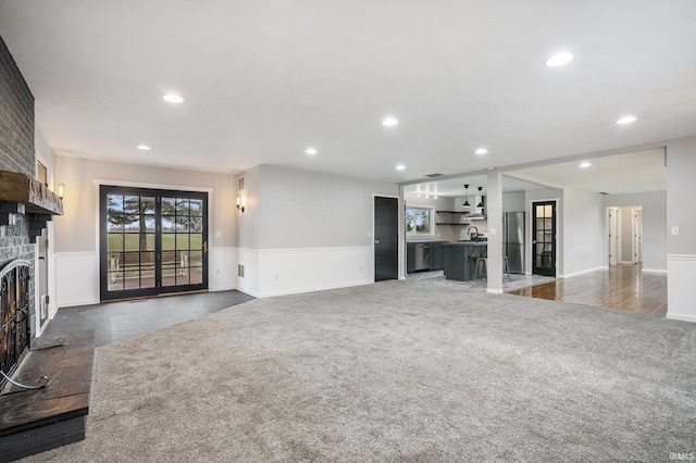 unfurnished living room with a fireplace and dark carpet