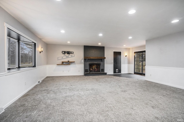 unfurnished living room with carpet flooring, a fireplace, and a healthy amount of sunlight