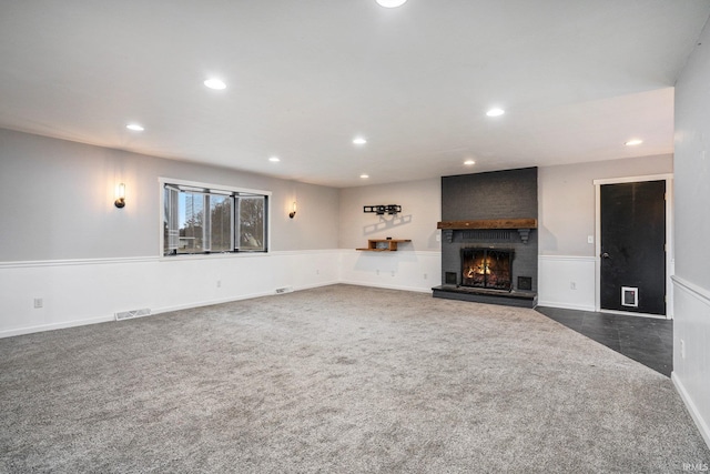 unfurnished living room with dark colored carpet and a fireplace