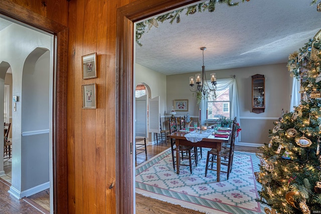 dining area featuring a textured ceiling, hardwood / wood-style flooring, and an inviting chandelier