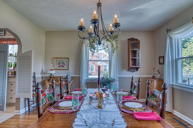 dining area with wood-type flooring, a textured ceiling, and a notable chandelier