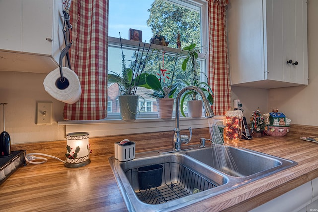 kitchen featuring white cabinets, butcher block counters, and sink