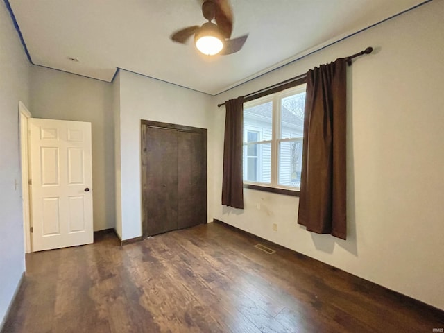 unfurnished bedroom with ceiling fan, dark wood-type flooring, and a closet