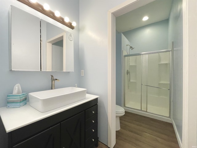 bathroom featuring wood-type flooring, vanity, toilet, and a shower with shower door