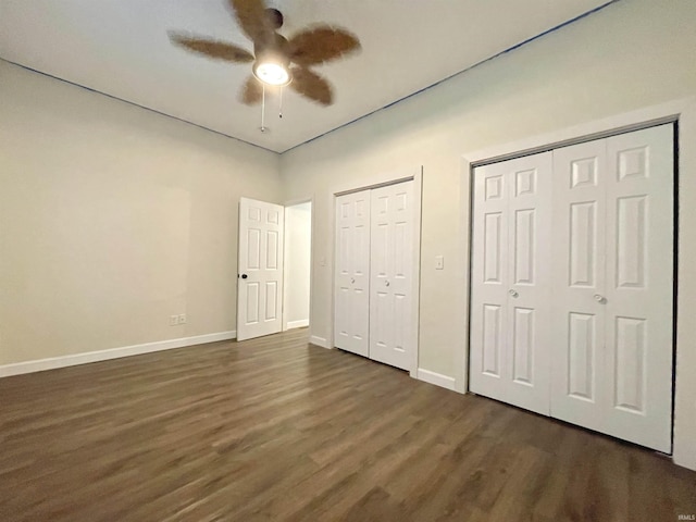 unfurnished bedroom featuring dark hardwood / wood-style floors, ceiling fan, and multiple closets