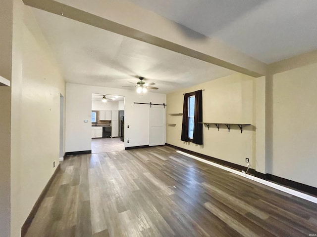 unfurnished living room featuring hardwood / wood-style floors, ceiling fan, a barn door, and a wealth of natural light