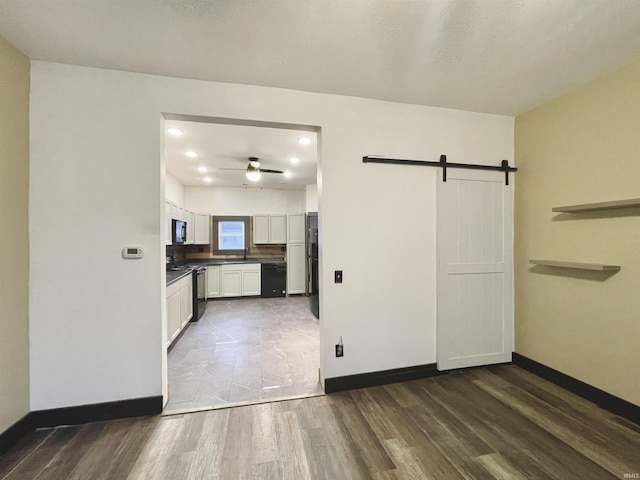 interior space with dark hardwood / wood-style flooring, a barn door, and ceiling fan