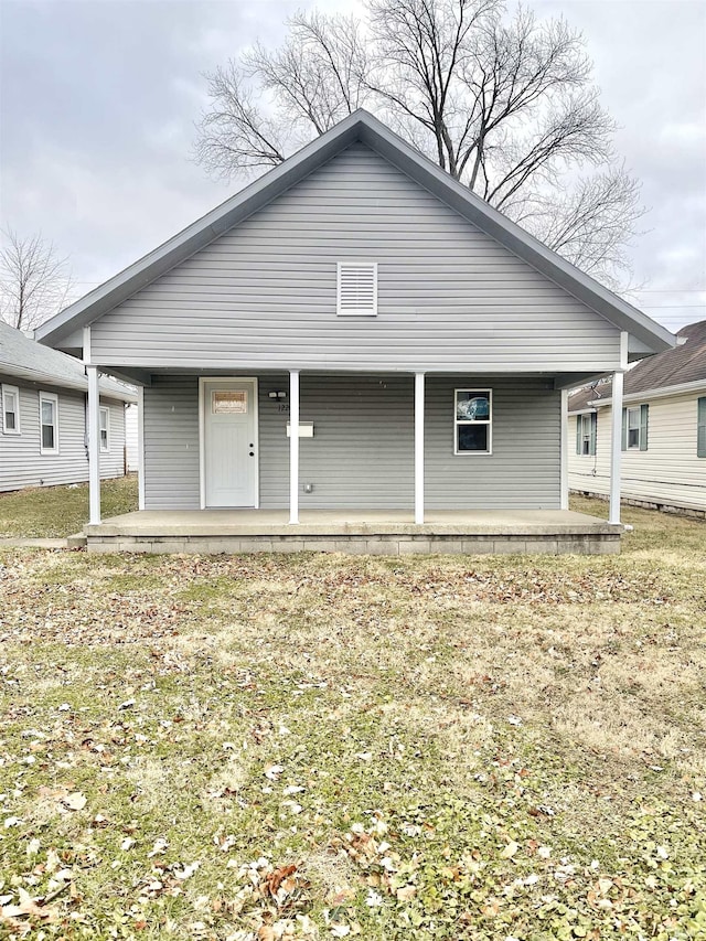 back of house with a lawn and covered porch