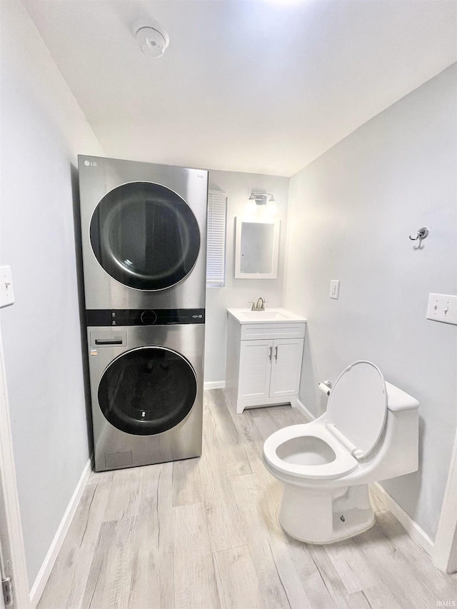 bathroom featuring vanity, hardwood / wood-style flooring, toilet, and stacked washer / drying machine