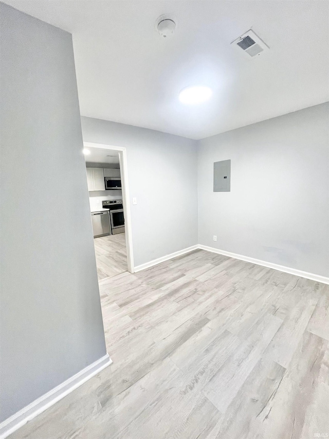 empty room with electric panel and light wood-type flooring