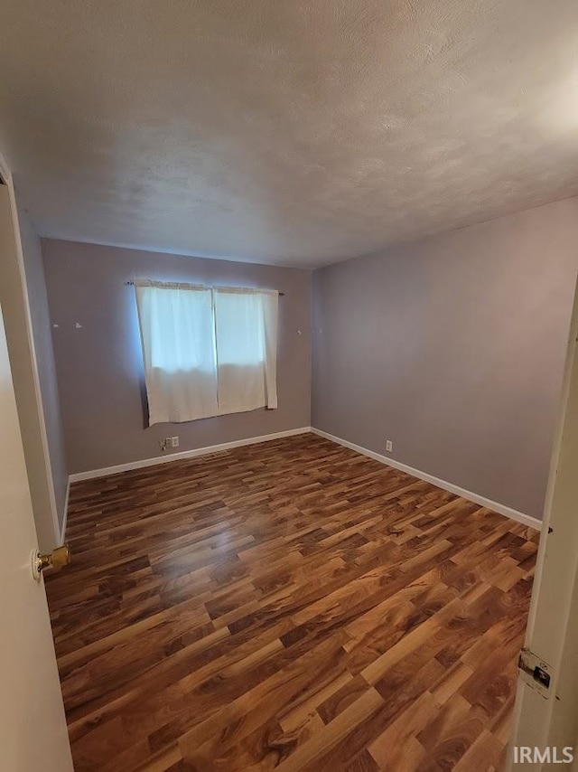 empty room with dark wood-type flooring and a textured ceiling