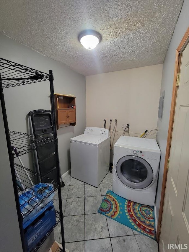 clothes washing area featuring washer and clothes dryer, light tile patterned floors, and a textured ceiling