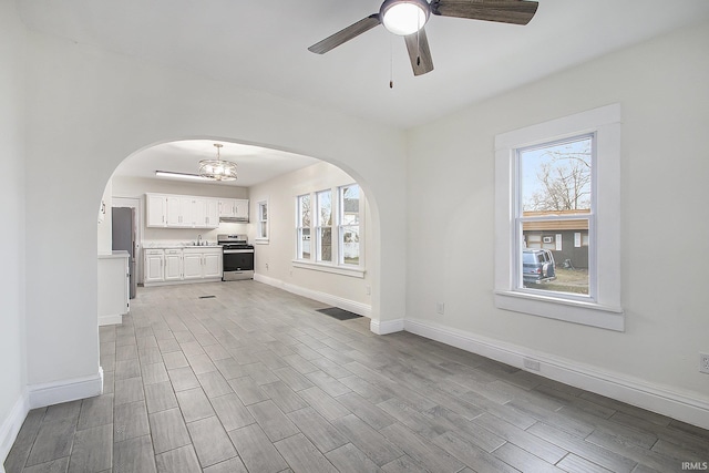 unfurnished living room featuring sink and ceiling fan with notable chandelier