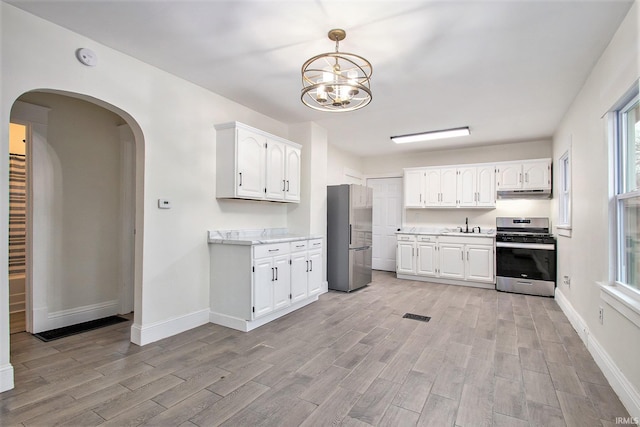 kitchen featuring stainless steel appliances, an inviting chandelier, white cabinets, light hardwood / wood-style floors, and hanging light fixtures