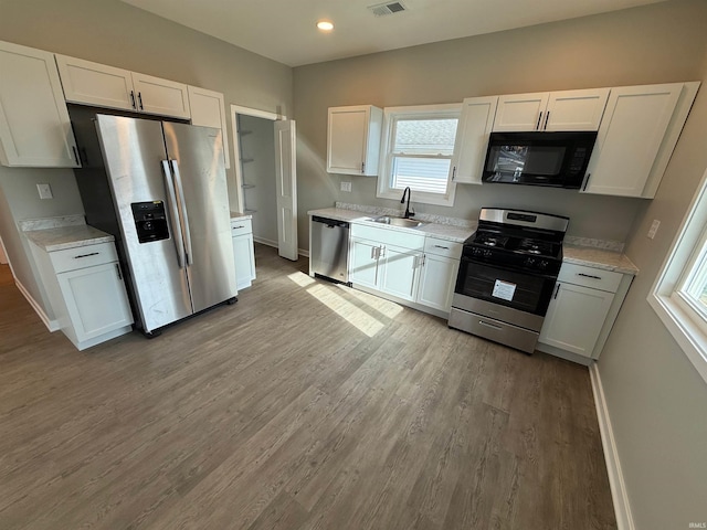 kitchen featuring white cabinetry, sink, light hardwood / wood-style flooring, and appliances with stainless steel finishes