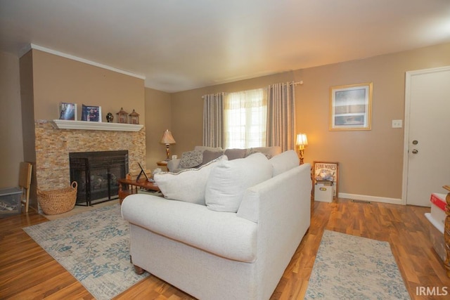 living area featuring visible vents, a fireplace, baseboards, and wood finished floors