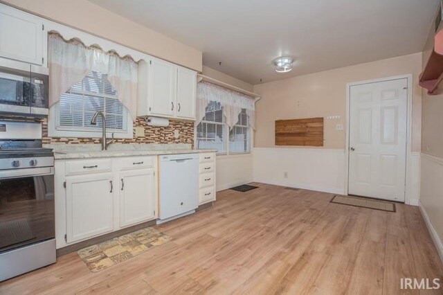 kitchen featuring light wood-style flooring, white cabinetry, stainless steel appliances, and a sink