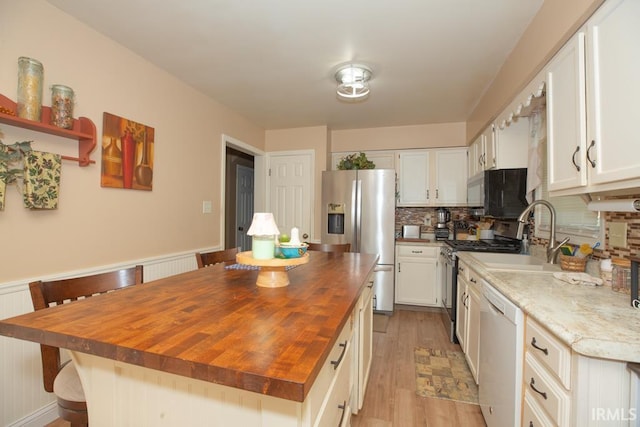 kitchen with butcher block counters, white cabinetry, appliances with stainless steel finishes, and a center island