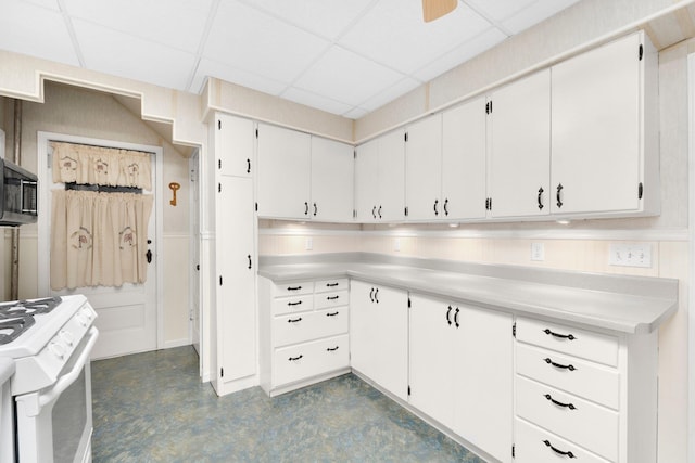 kitchen featuring a paneled ceiling, white range, and white cabinetry