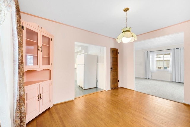 unfurnished dining area featuring ornamental molding and light wood-type flooring