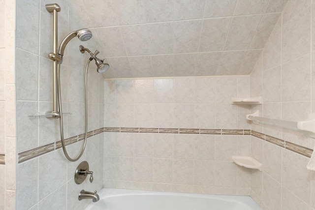 bathroom with lofted ceiling and tiled shower / bath