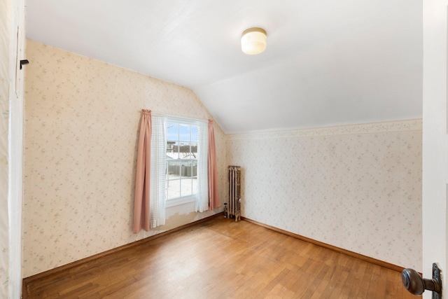 additional living space with radiator heating unit, lofted ceiling, and hardwood / wood-style flooring