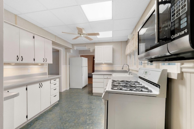 kitchen featuring a paneled ceiling, white appliances, sink, ceiling fan, and white cabinetry