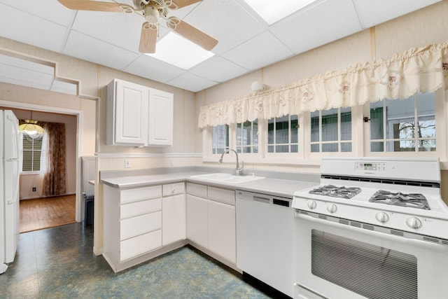 kitchen with a paneled ceiling, white cabinetry, white appliances, and sink