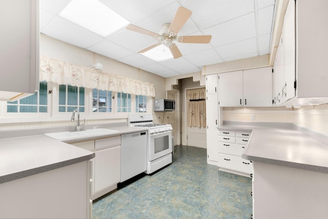 kitchen featuring a paneled ceiling, white cabinets, white appliances, and sink