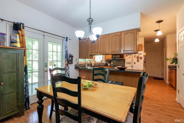 dining space with a chandelier, sink, light hardwood / wood-style flooring, and french doors