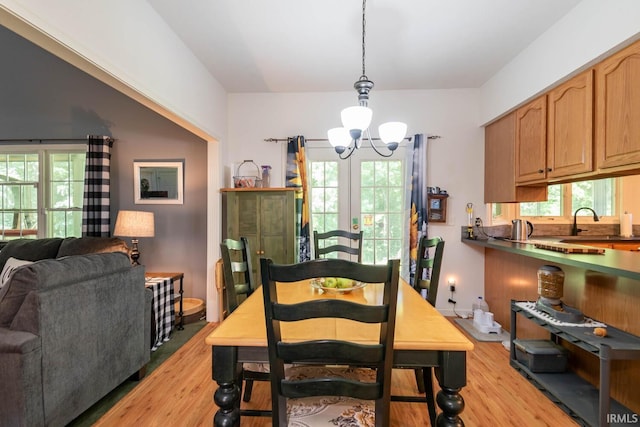 dining area featuring sink, plenty of natural light, light wood-type flooring, and a notable chandelier